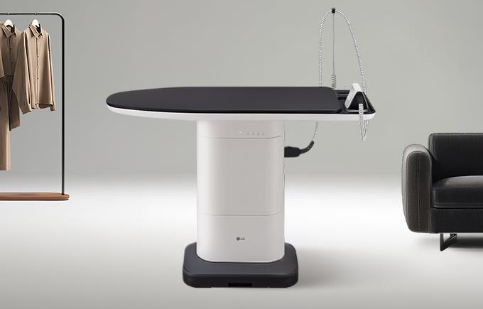 화이트톤 공간에 왼쪽에는 옷걸이에 옷이 걸려있고, 오른쪽엔 검은 소파가 살짝 놓여 있으며 가운데에는 테이블처럼 보이는 블랙&화이트 시스템 아이어닝이 설치돼있음